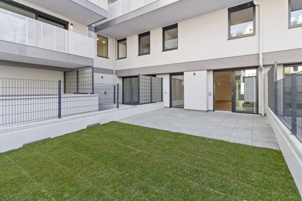 Private Terrasse mit Rasenfläche und Zugang zu den Innenräumen eines modernen Gebäudes.