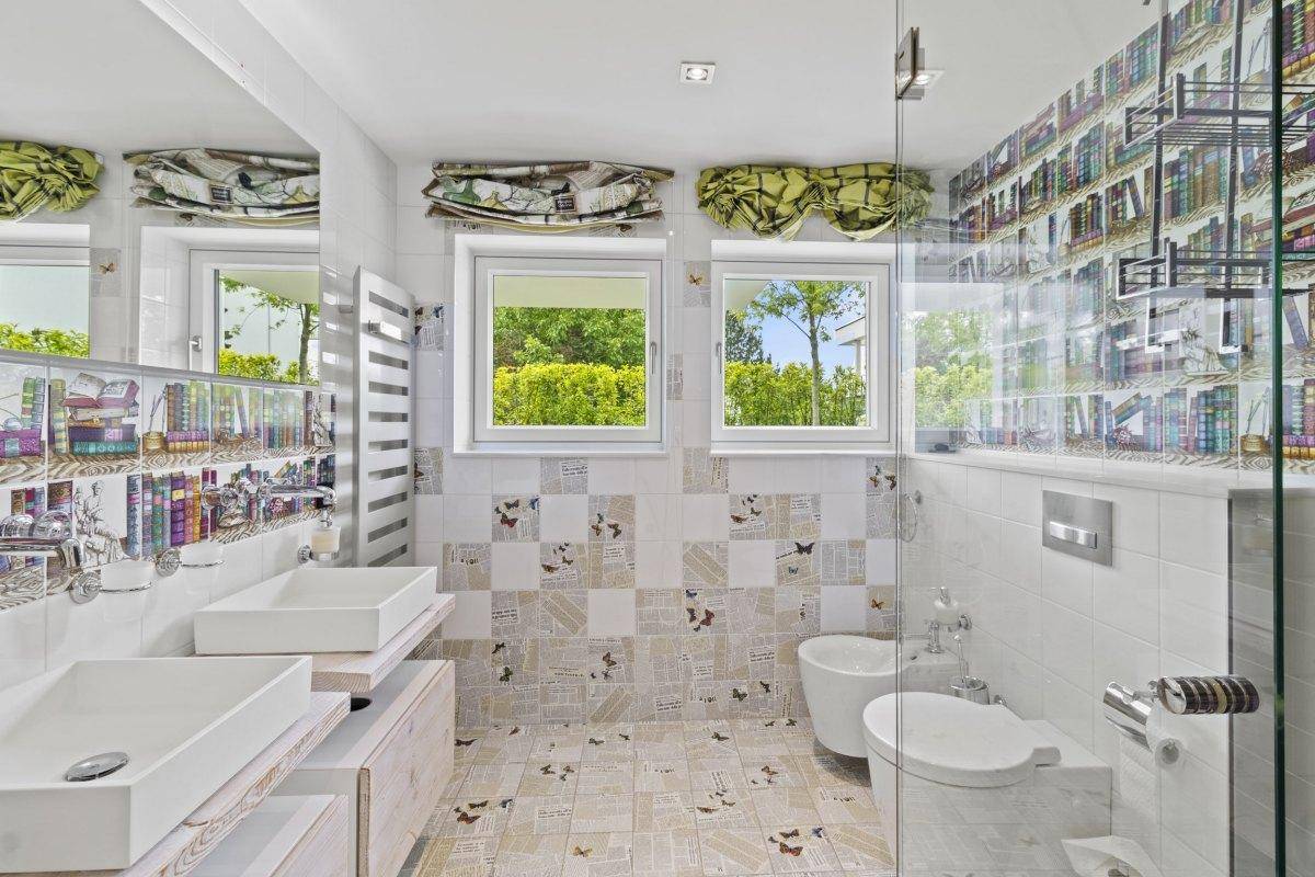 Individuell gestaltetes Badezimmer mit zwei Aufsatzwaschbecken, Dusche und dekorativen Fliesen.