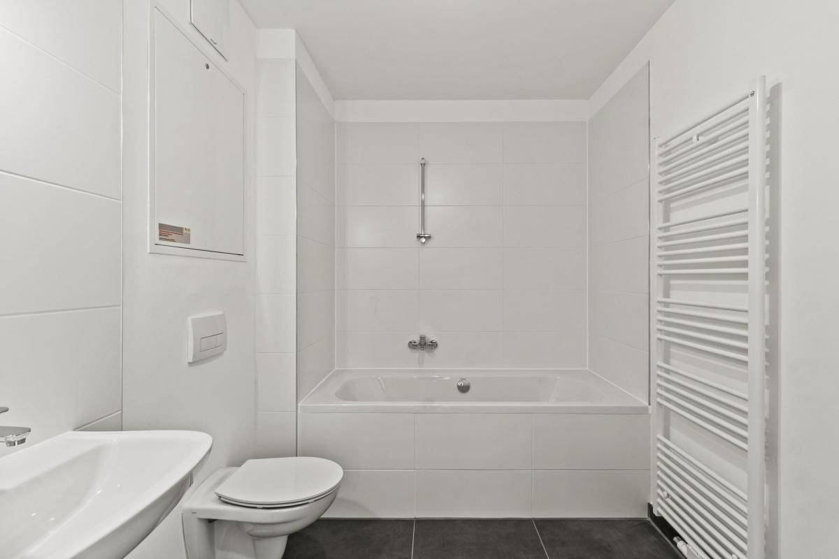 Modernes Badezimmer mit Badewanne, WC, Waschbecken und beheiztem Handtuchhalter.