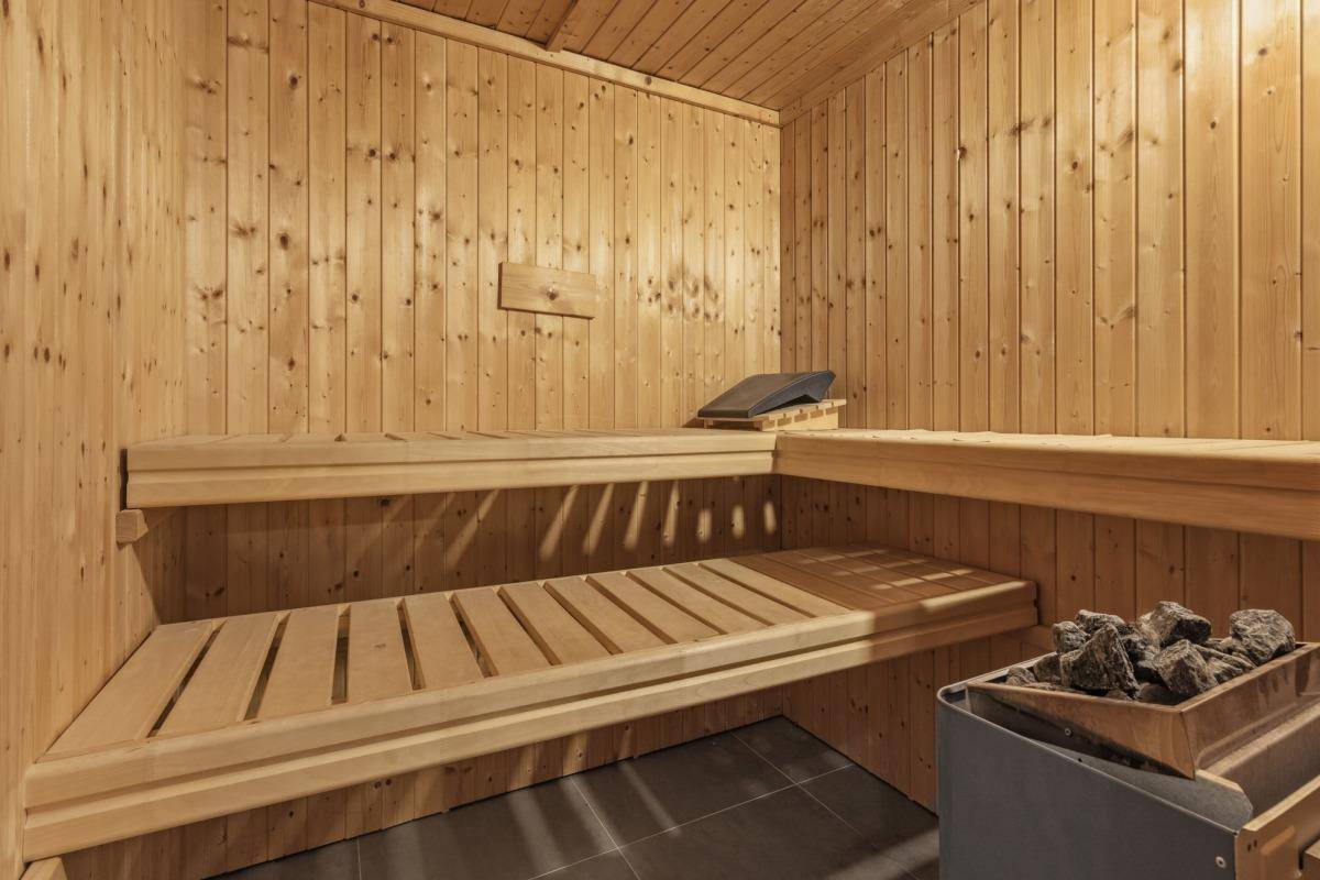 Gemütliche Holzsauna mit mehreren Bänken und traditionellem Saunaofen für Wellness.