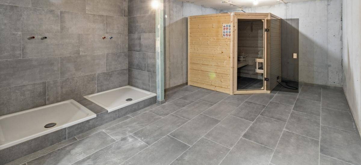 Wellnessbereich mit Sauna und zwei Duschbereichen in einem modernen Ambiente.