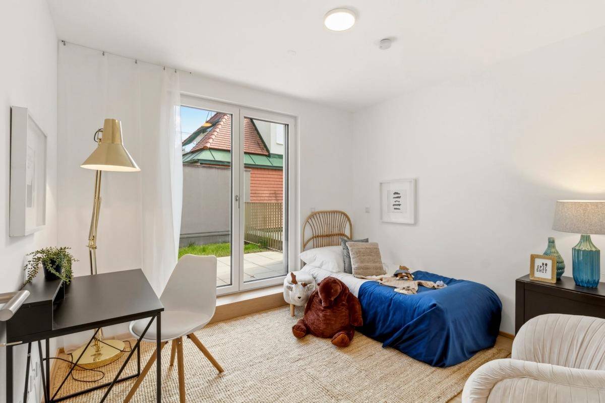 Helles Kinder- oder Gästezimmer mit Zugang zur Terrasse und Blick ins Grüne.