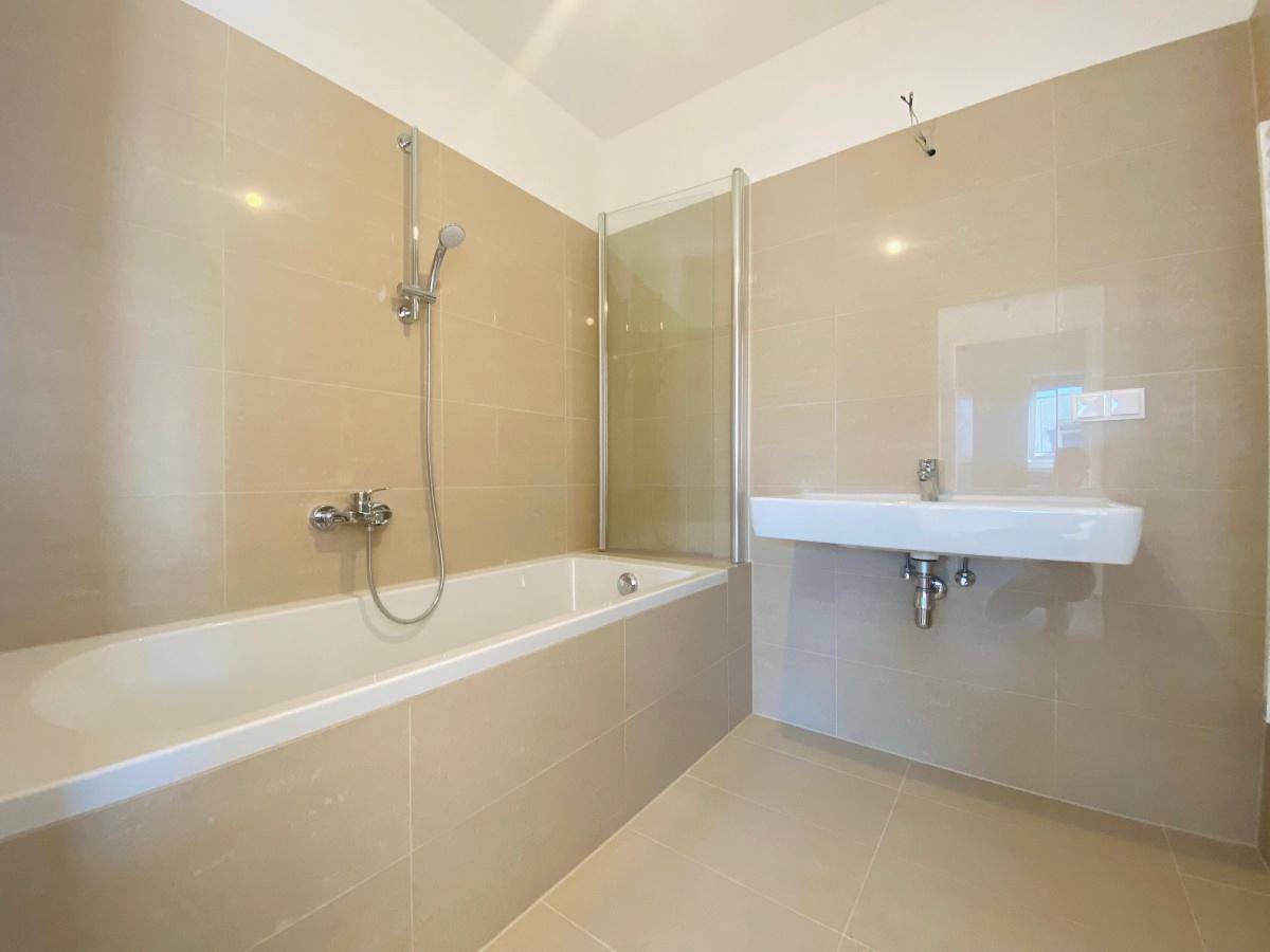 Modernes Badezimmer mit Badewanne, Duschabtrennung und beigefarbenen Fliesen.
