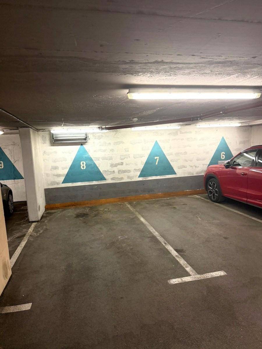 Weitere Ansicht der Tiefgarage mit nummerierten Parkplätzen und Betonwänden.