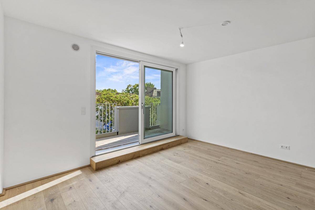 Heller Wohnraum mit Parkettboden und großem Schiebefenster zum Balkon.