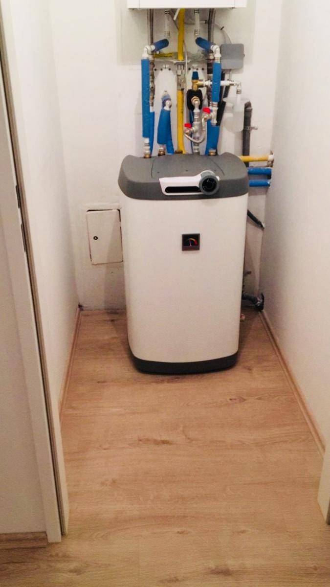 Technikraum mit Heizungsanlage und sichtbaren Rohren auf Laminatboden.