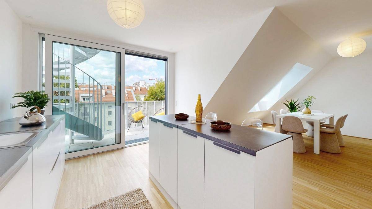 Helle Küche mit Kücheninsel, modernen Geräten und Schiebetür zum Balkon.