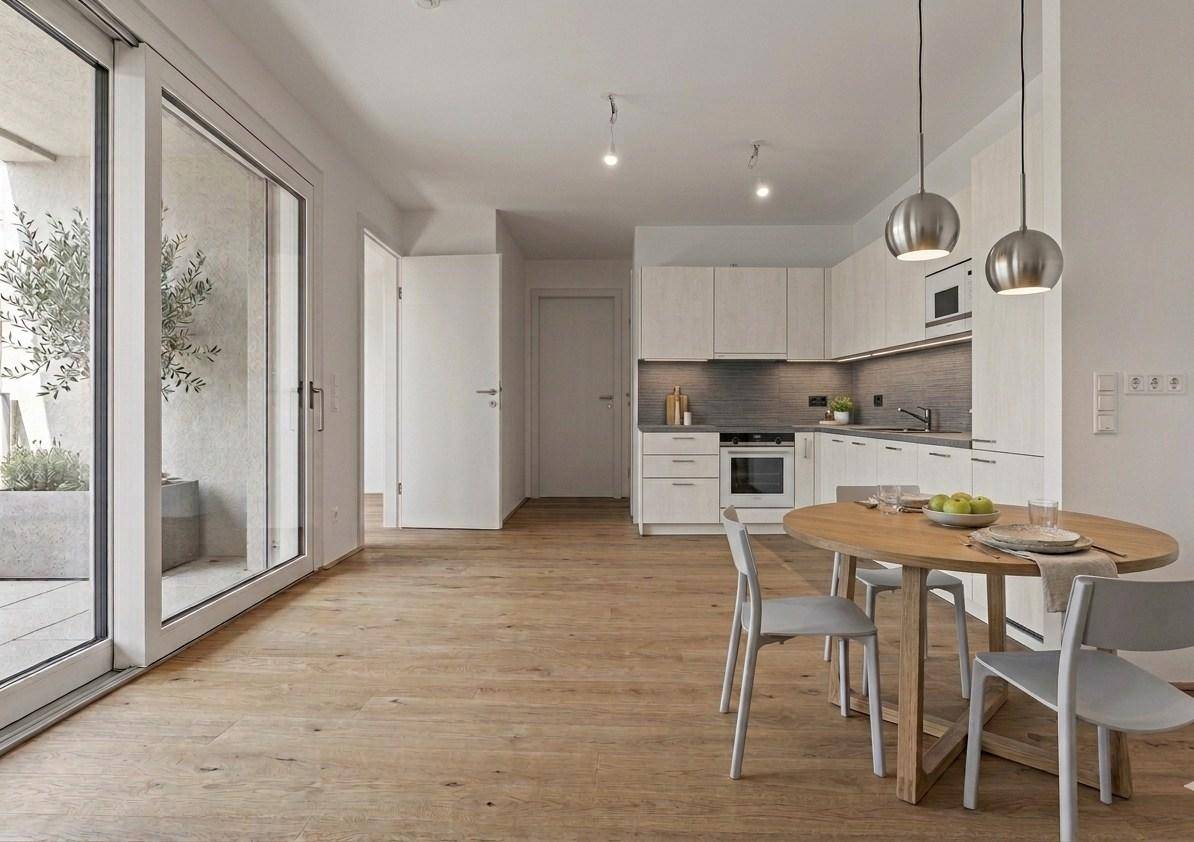 Heller offener Wohn-Essbereich mit integrierter moderner Küche, Holzboden und Zugang zum Balkon.