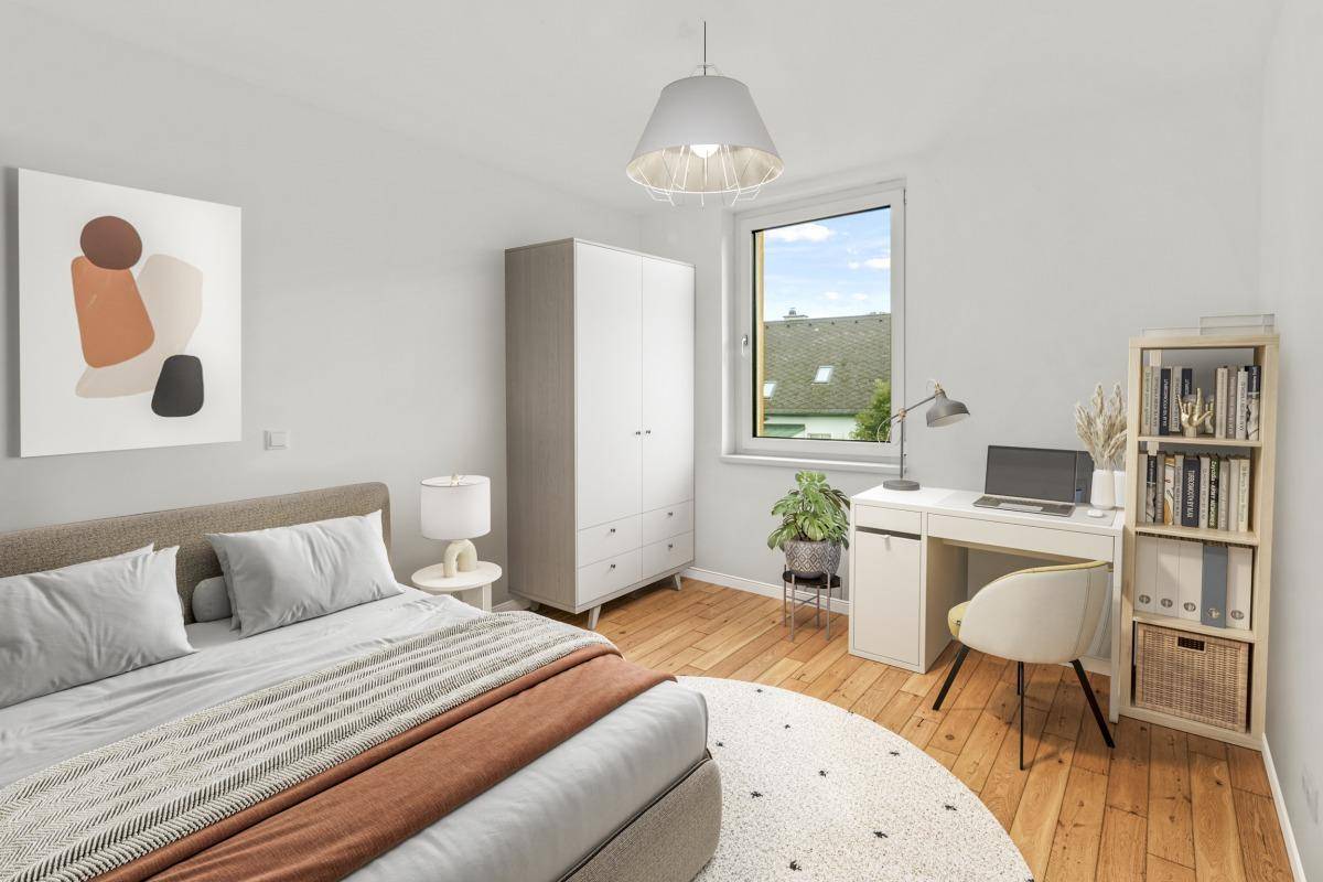 Schlafzimmer mit Schreibtisch, Holzboden und Fensterblick ins Grüne.
