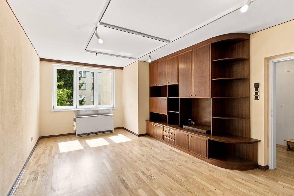Geräumiges Wohnzimmer mit Holzboden, Einbauschränken und viel Tageslicht durch das Fenster.