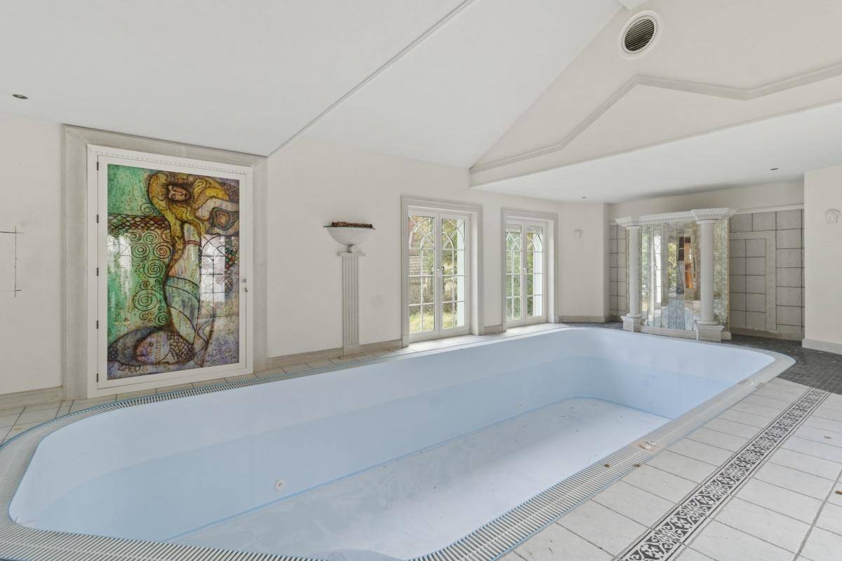 Geräumiger Innenpoolbereich mit hohen Decken, großen Fenstern und künstlerisch gestalteter Tür.