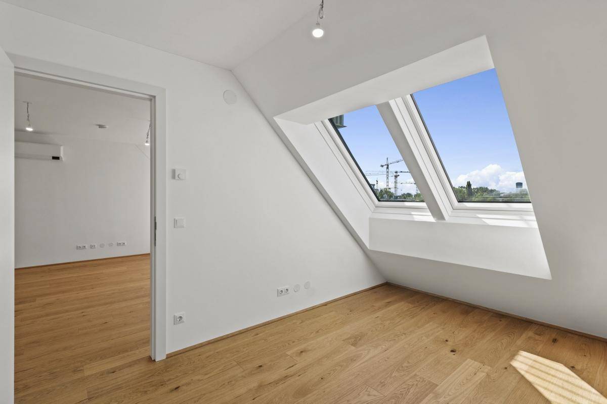 Helles Schlafzimmer mit Holzboden und großem Dachfenster, das viel Tageslicht spendet.