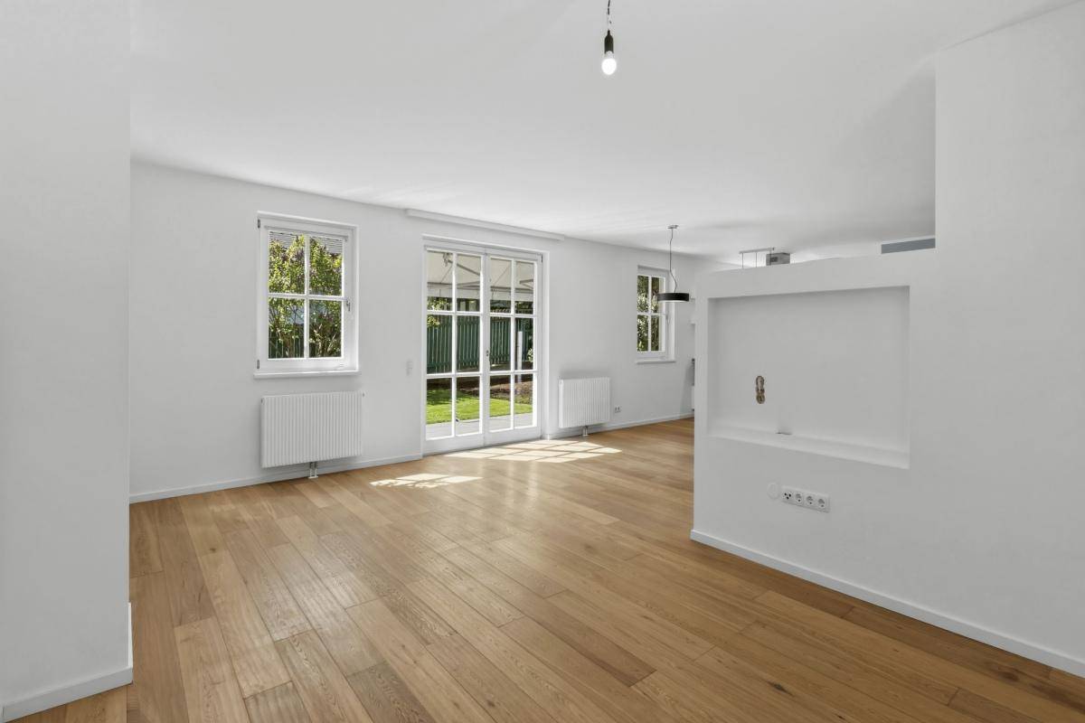 Geräumiges Wohnzimmer mit Holzboden, großen Fenstern und direktem Zugang zum Garten.