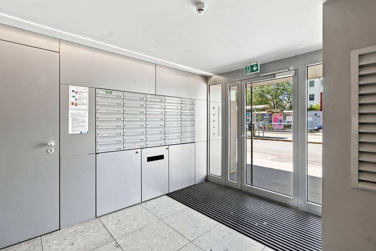 Moderner Eingangsbereich mit Briefkästen, Gegensprechanlage und Zugang zur Straße.