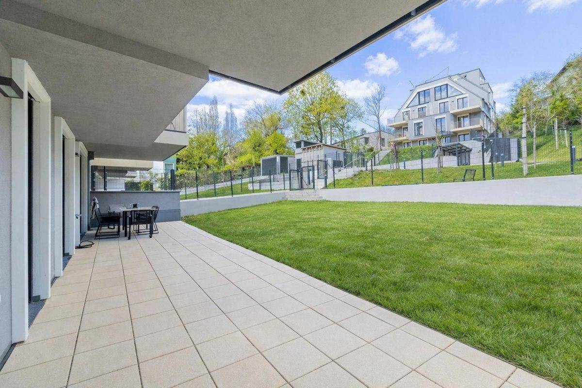 Geräumige Terrasse mit Fliesenboden und Blick auf den Garten und die umliegende Bebauung.