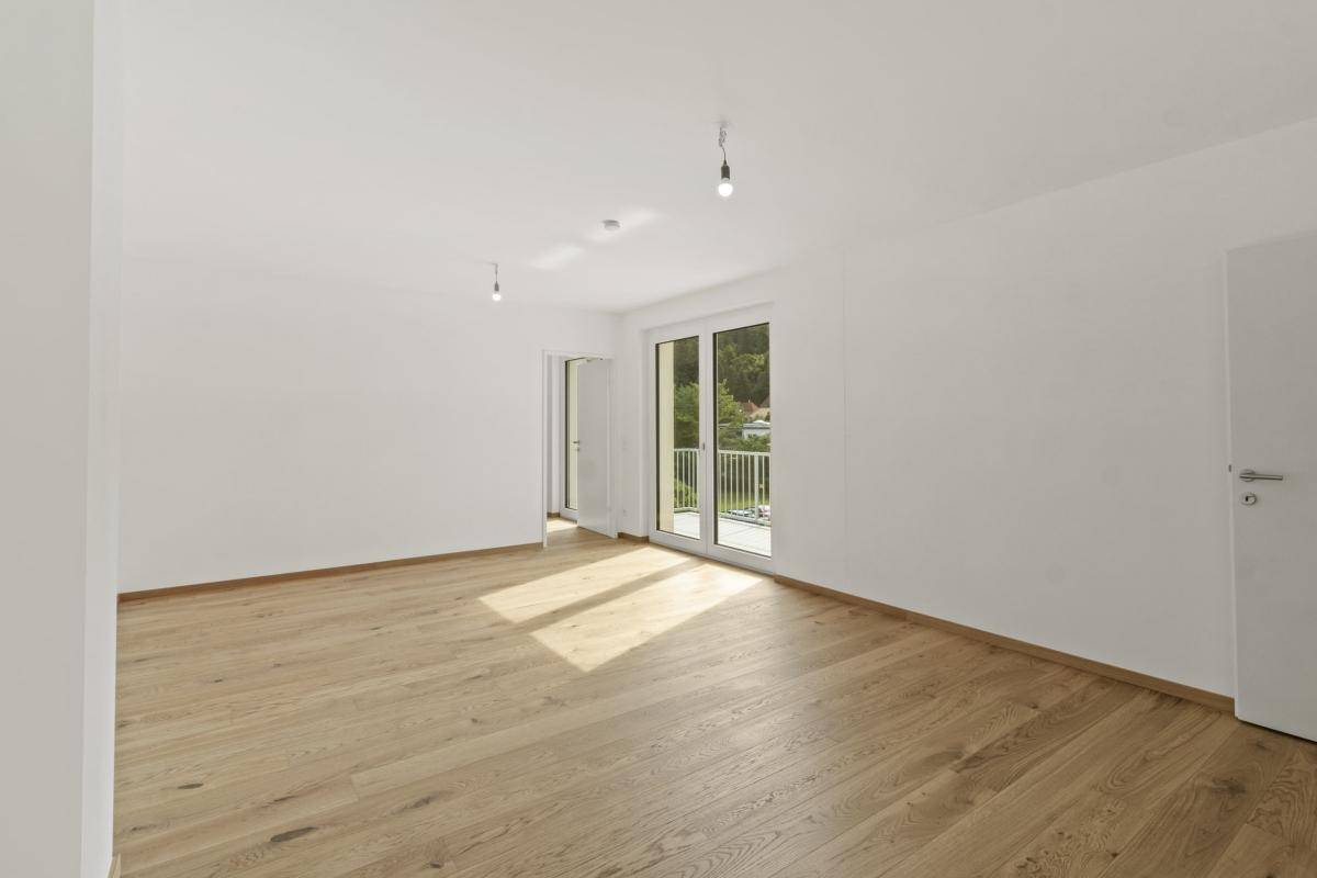 Heller Wohnraum mit Holzboden und zwei Zugängen zu Außenbereichen, ideal für viel Tageslicht.