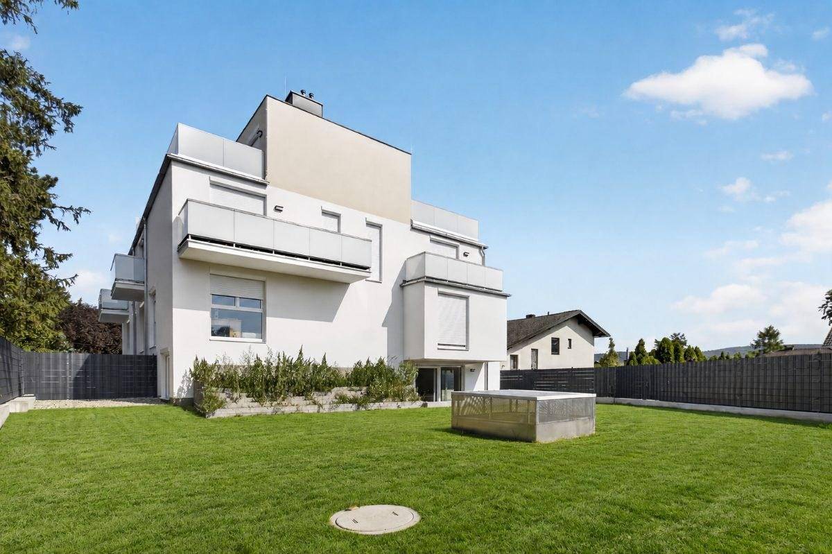 Rückansicht des modernen Gebäudes mit großem Garten und gepflegter Rasenfläche.