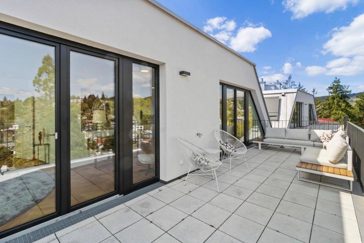 Geräumige Terrasse mit modernen Sitzgelegenheiten und weitem Blick auf die Landschaft und Stadt.