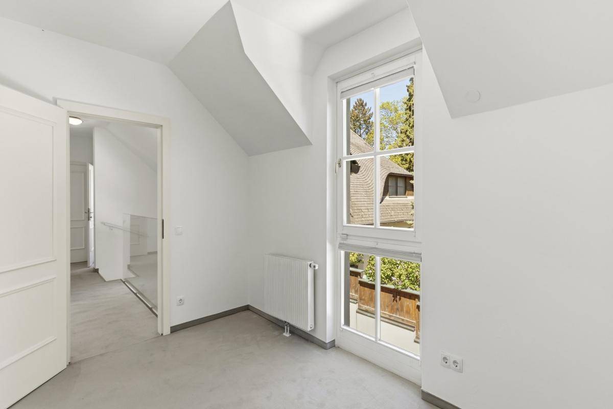 Helles Schlafzimmer mit Teppichboden, großen Fenstern und schrägen Wänden im Dachgeschoss.