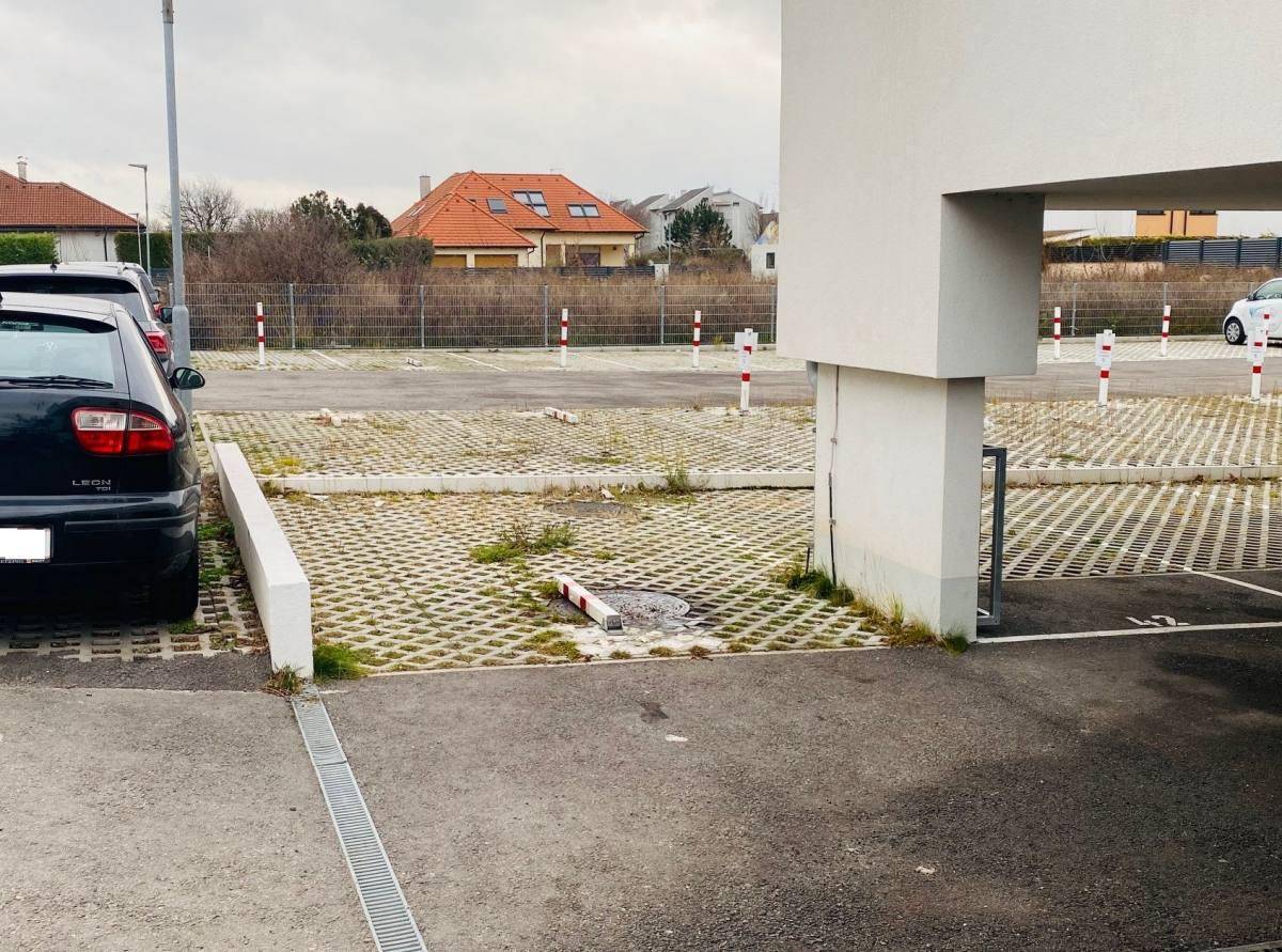 Außenparkplätze mit Rasengittersteinen und einem Teil des Gebäudes im Hintergrund.