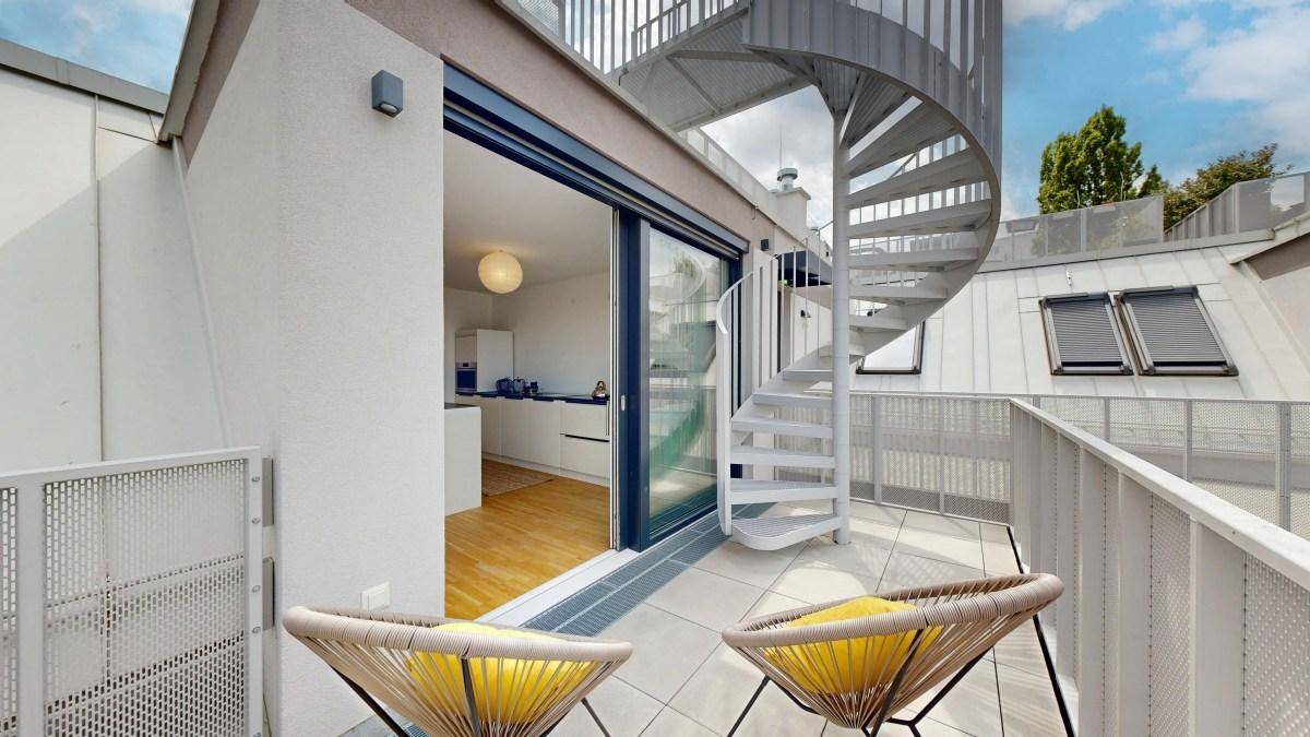 Balkon mit Sitzgelegenheiten und Zugang zu einer modernen Küche im Innenbereich.