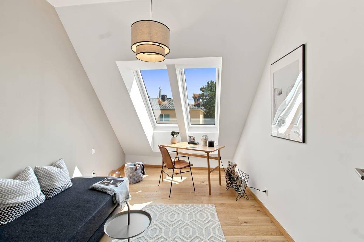 Helles Arbeitszimmer mit Holzboden, Dachfenstern und einem modernen Schreibtischbereich.