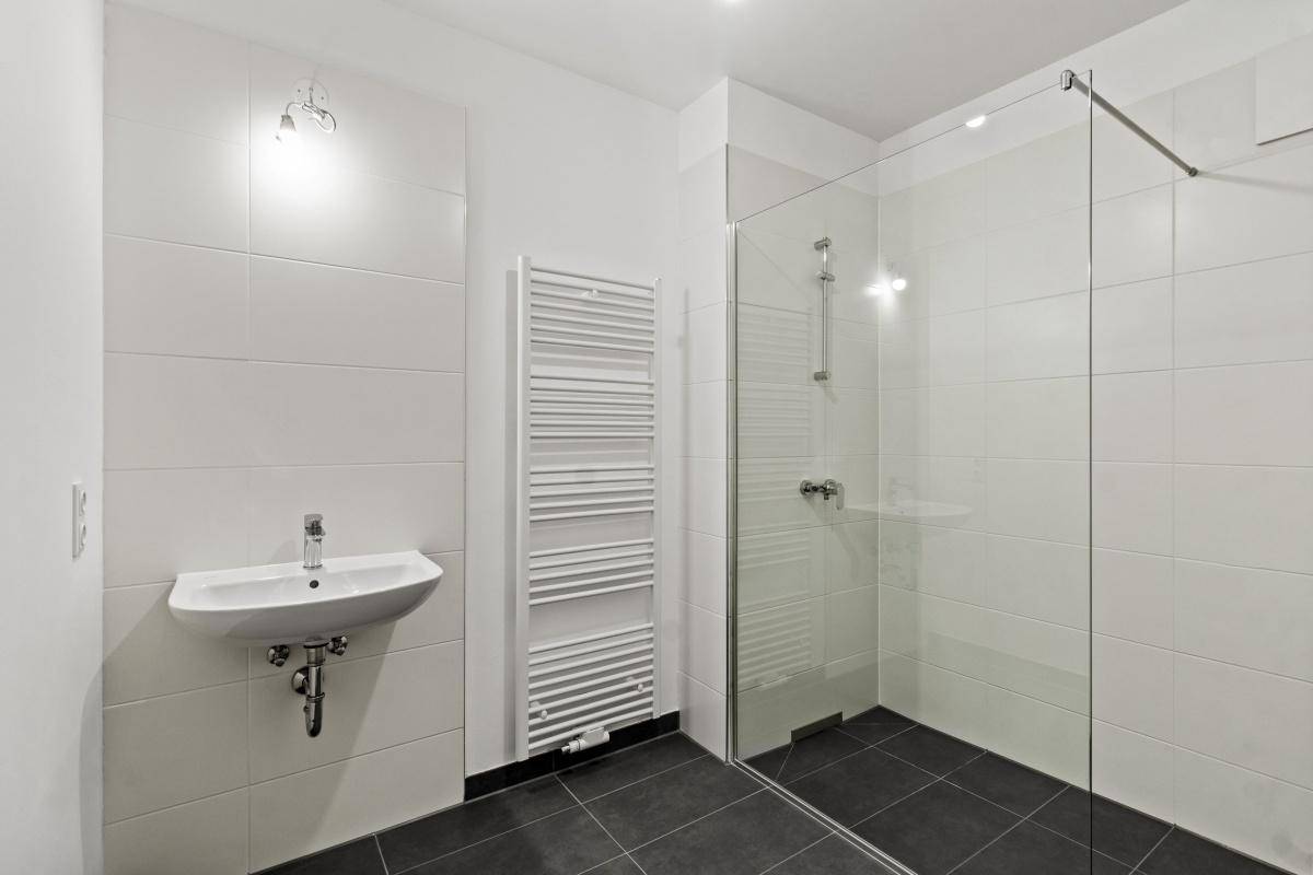 Modernes Badezimmer mit Waschbecken, Dusche und weißem Handtuchheizkörper.