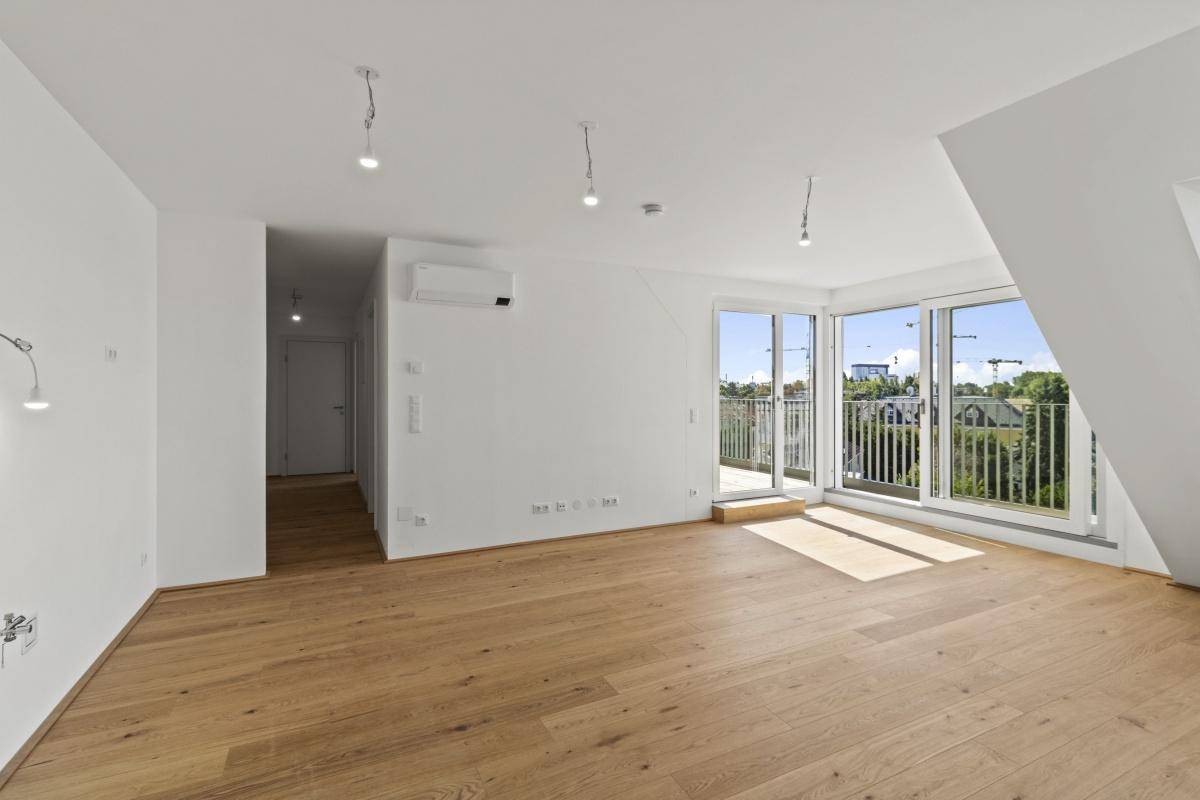 Heller Wohnraum mit Holzboden, Klimaanlage und großen Fenstern, die viel Tageslicht hereinlassen.