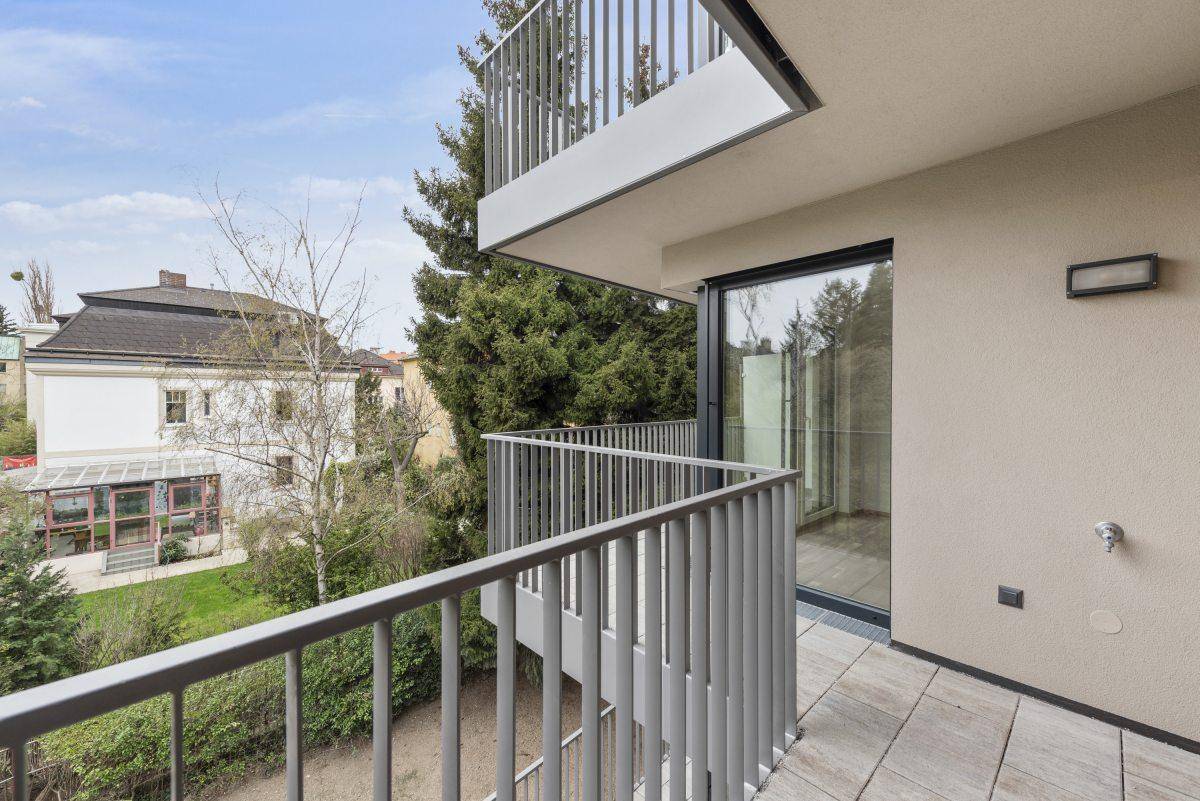 Balkon mit Blick auf Bäume und umliegende Gebäude, ausgestattet mit einem modernen Geländer.