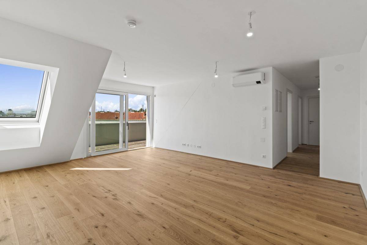 Geräumiger Wohnbereich mit Holzboden, Klimaanlage und Zugang zu einem Außenbereich.