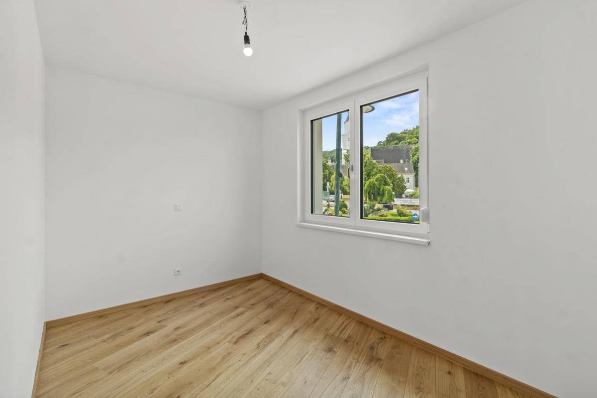 Lichtdurchflutetes Schlafzimmer mit Parkettboden und Fenster mit Blick auf die Landschaft.