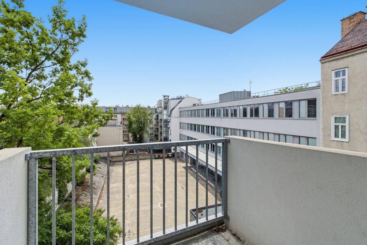 Balkon mit Metallgeländer und Blick auf umliegende Gebäude und Bäume.