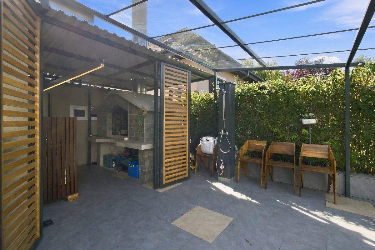 Überdachter Grillbereich mit Außenküche und Dusche im Garten.