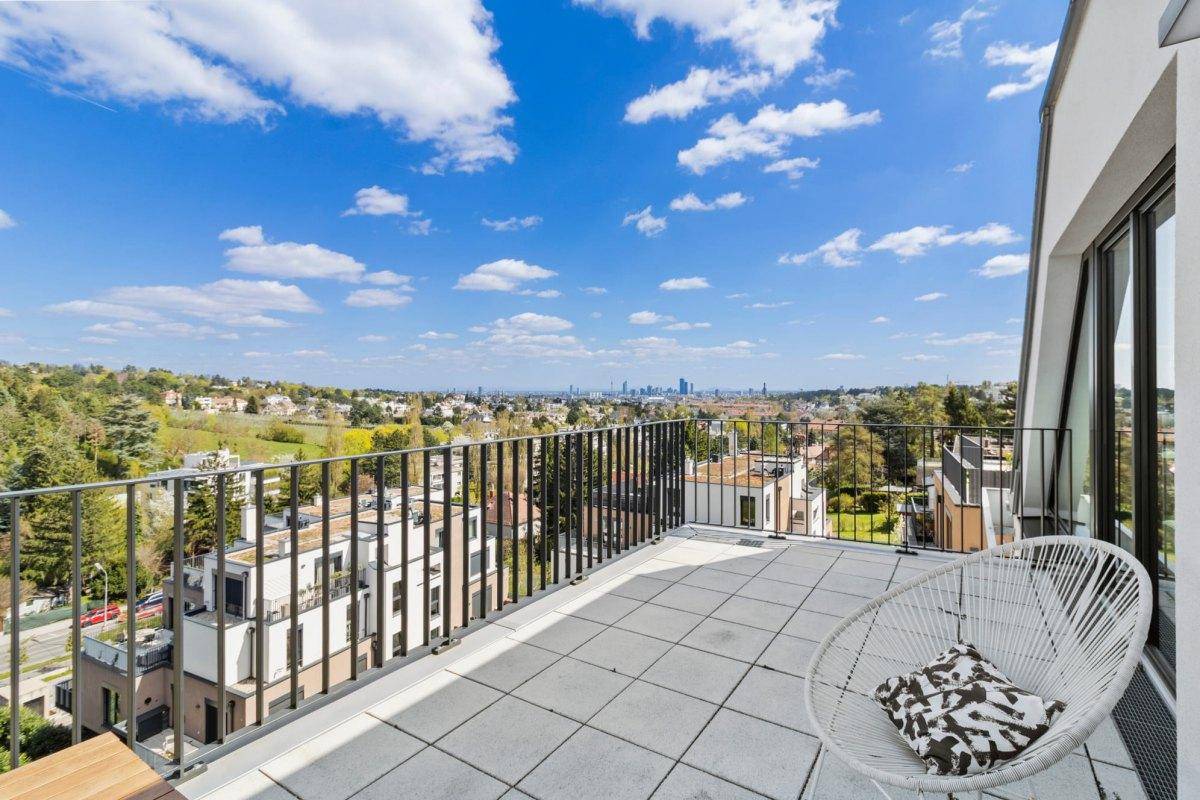 Sonniger Terrassenbereich mit Fliesenboden und weitem Blick über die umliegende Landschaft und Stadt.