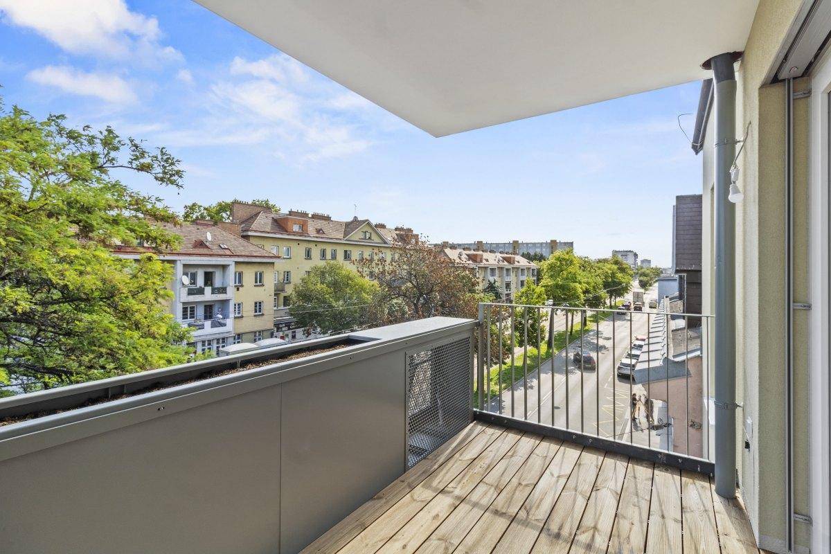 Geräumiger Balkon mit Holzboden und Blick auf die umliegende Stadtlandschaft und Straße.