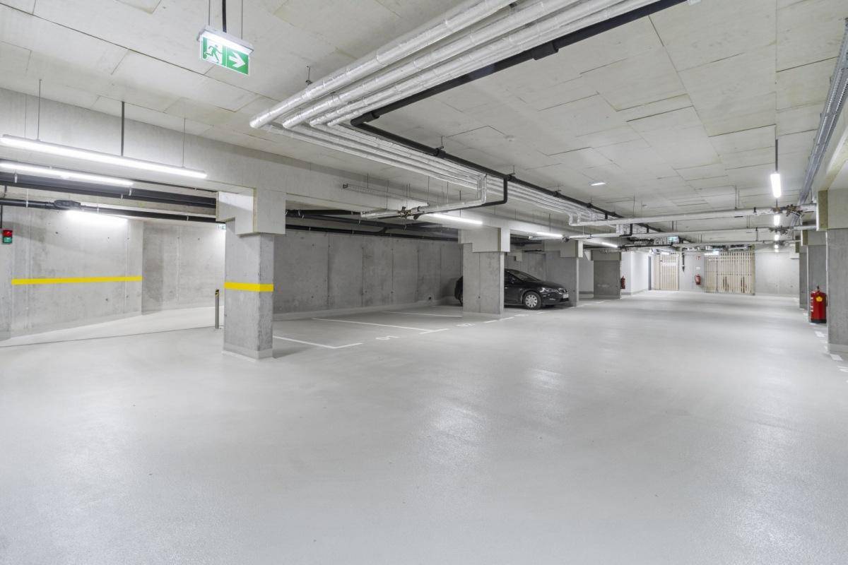 Helle und saubere Tiefgarage mit markierten Stellplätzen und moderner Beleuchtung.