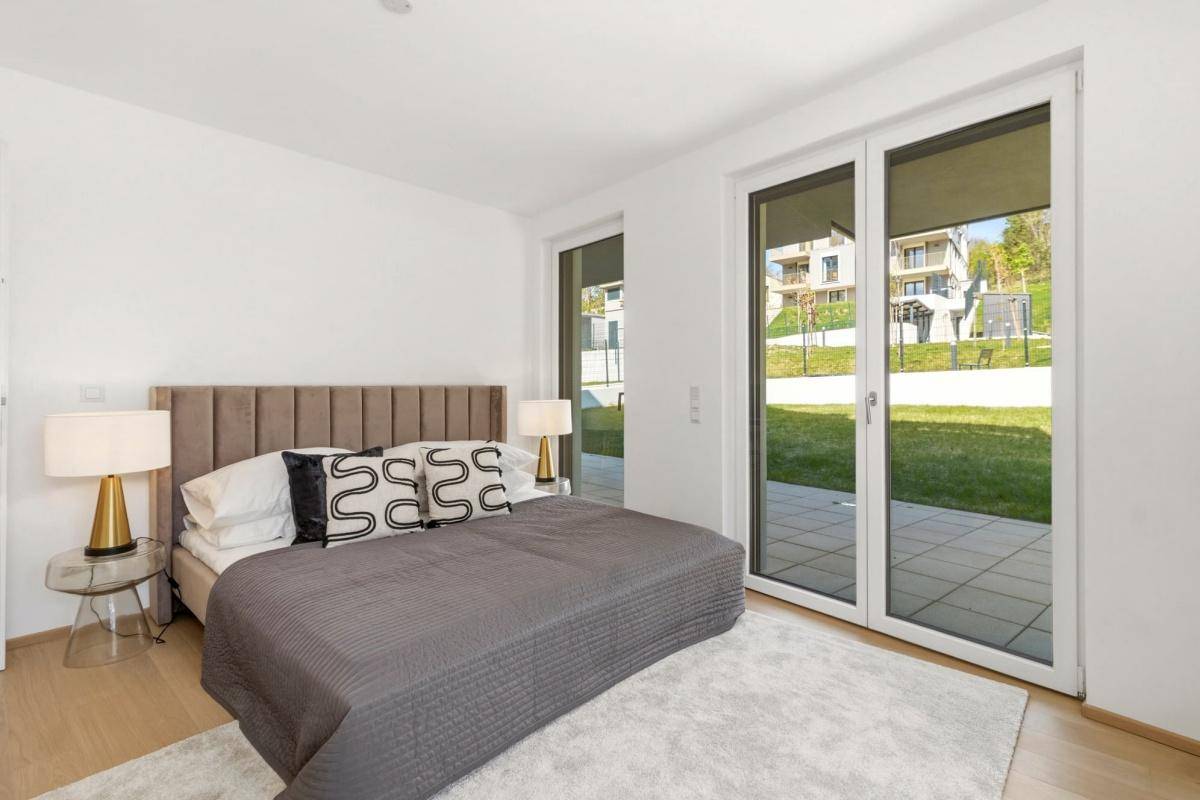 Modernes Schlafzimmer mit großzügigen Fenstern und direktem Zugang zur Terrasse und Garten.