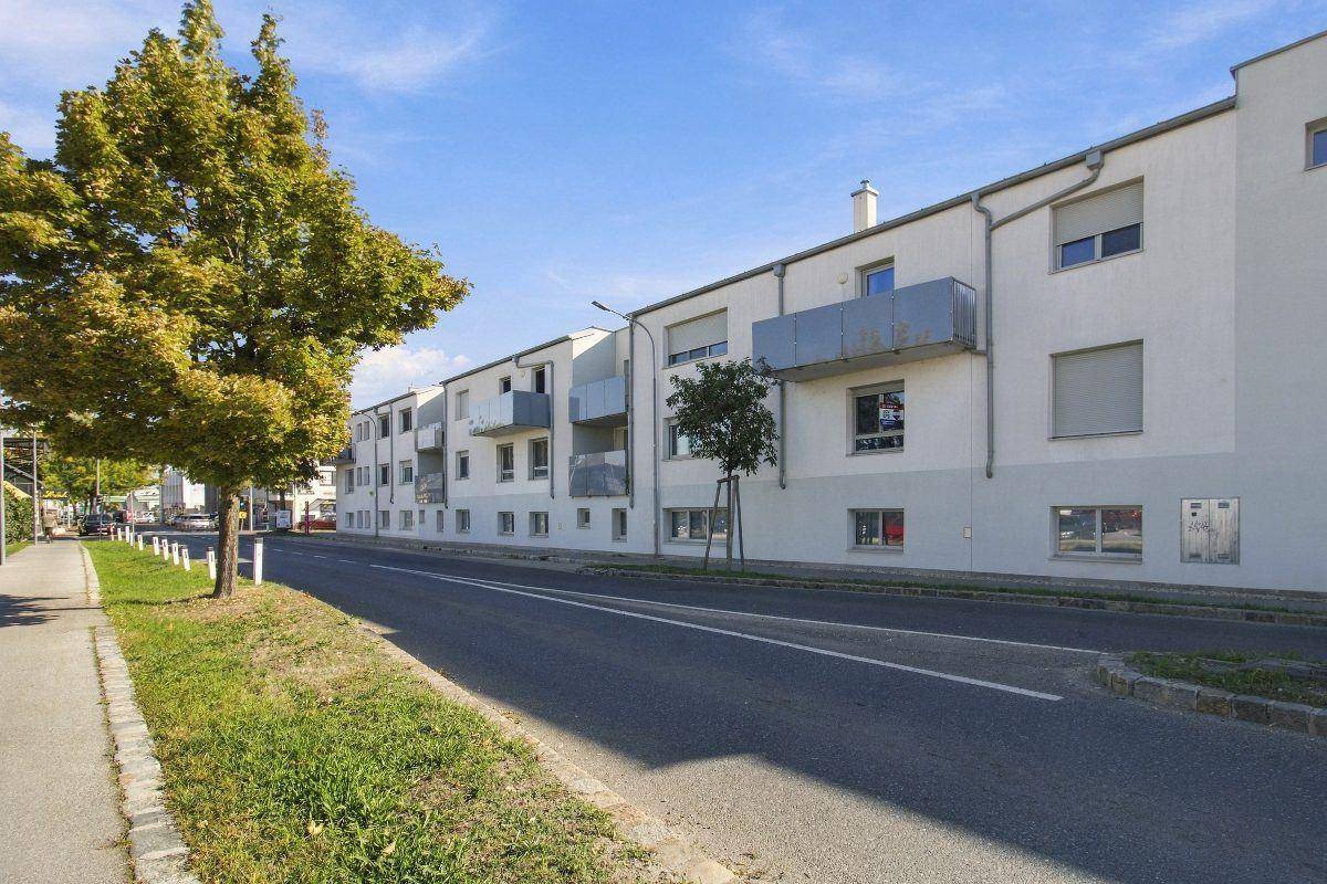 Straßenansicht eines Wohngebäudes mit mehreren Etagen, Balkonen und gepflegter Umgebung.