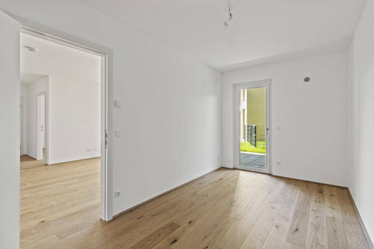 Lichtdurchflutetes Zimmer mit Parkettboden und Zugang zu einem Außenbereich.