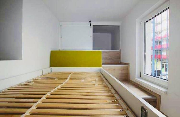 Schlafbereich mit Hochbett, grünem Kopfteil und Blick aus dem Fenster auf die Umgebung.
