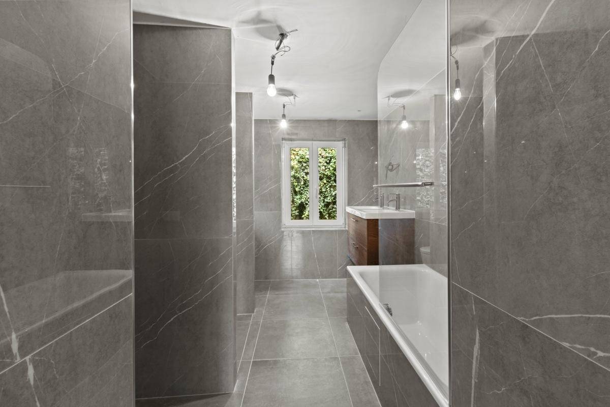 Modernes Badezimmer mit grauen Marmorfliesen und Badewanne.