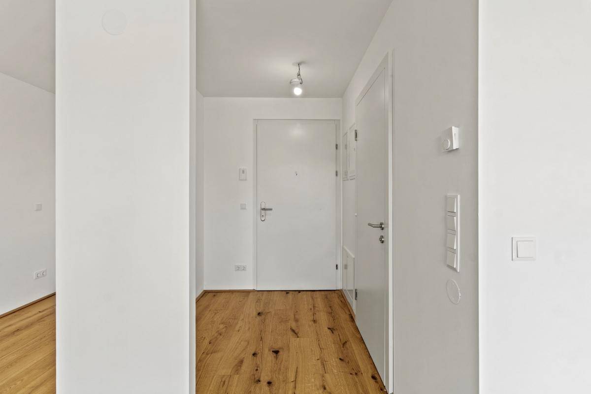 Heller Eingangsbereich mit Holzboden und weißen Türen, führt in die Wohnung.