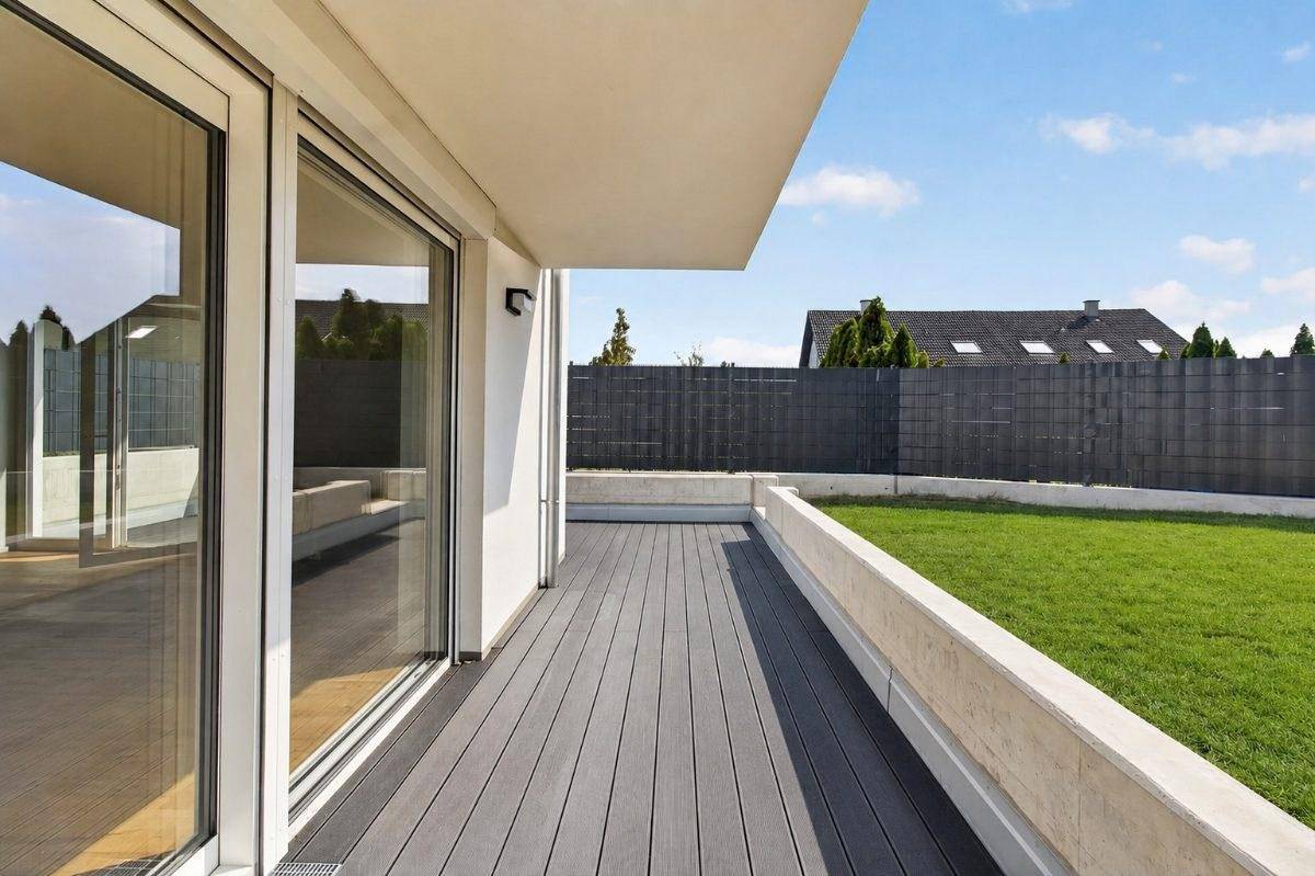 Moderne Terrasse mit Holzdielen und Blick auf den privaten Garten.
