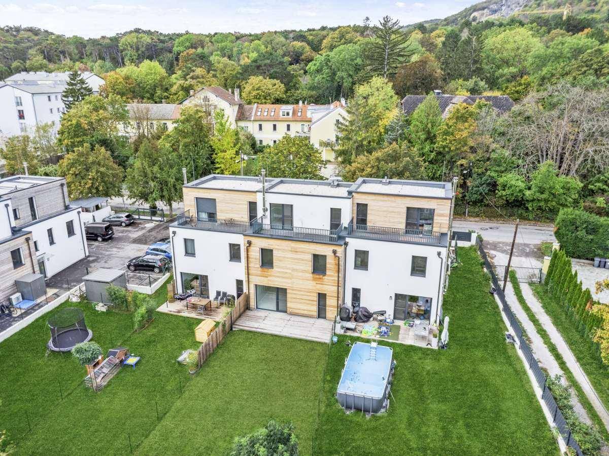 Rückansicht moderner Reihenhäuser mit privaten Gärten und einem kleinen Aufstellpool.
