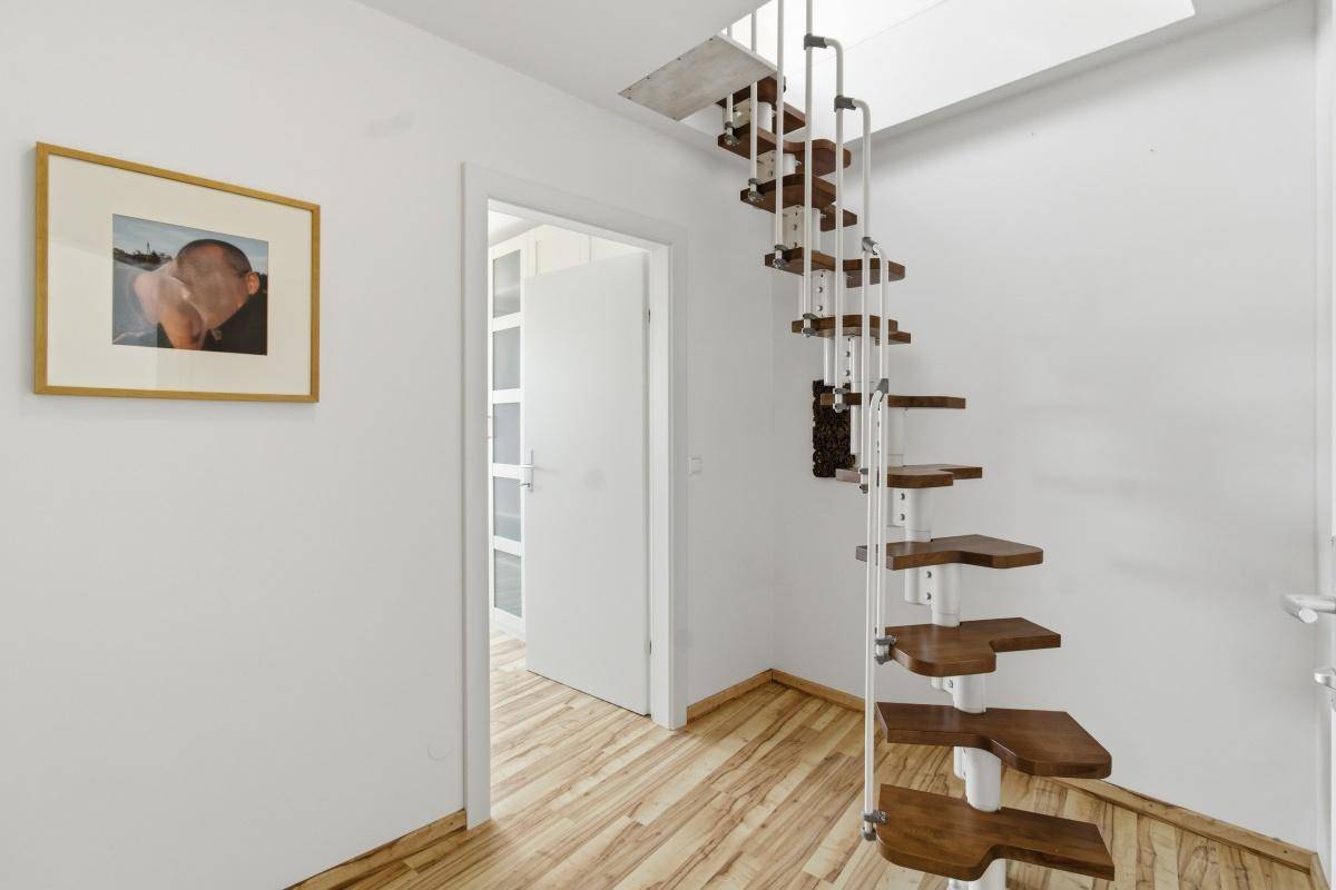 Heller Flur mit Holzboden und einer eleganten Wendeltreppe, die in das obere Stockwerk führt.