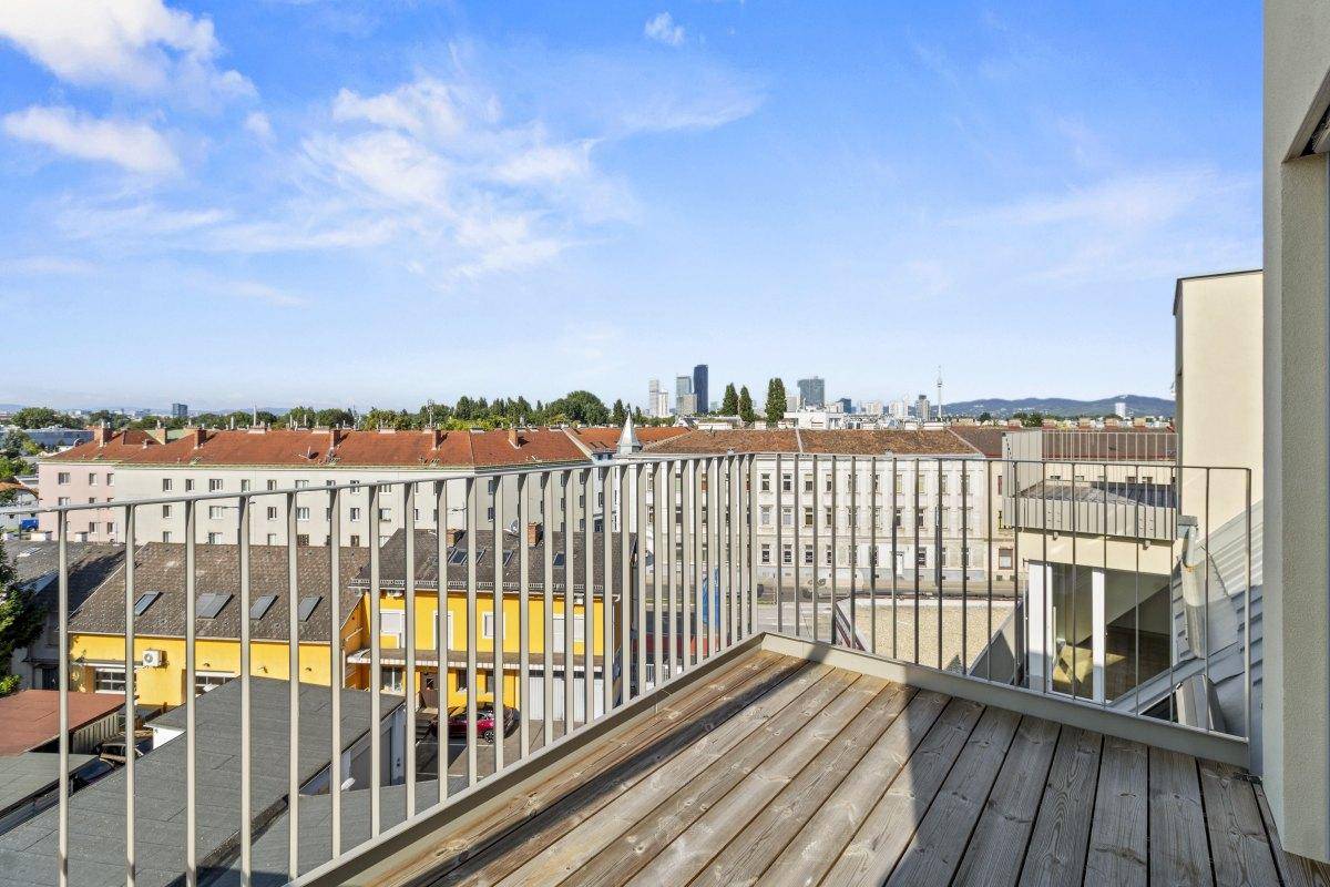 Geräumige Dachterrasse mit Holzboden und weitem Blick über die Stadt.