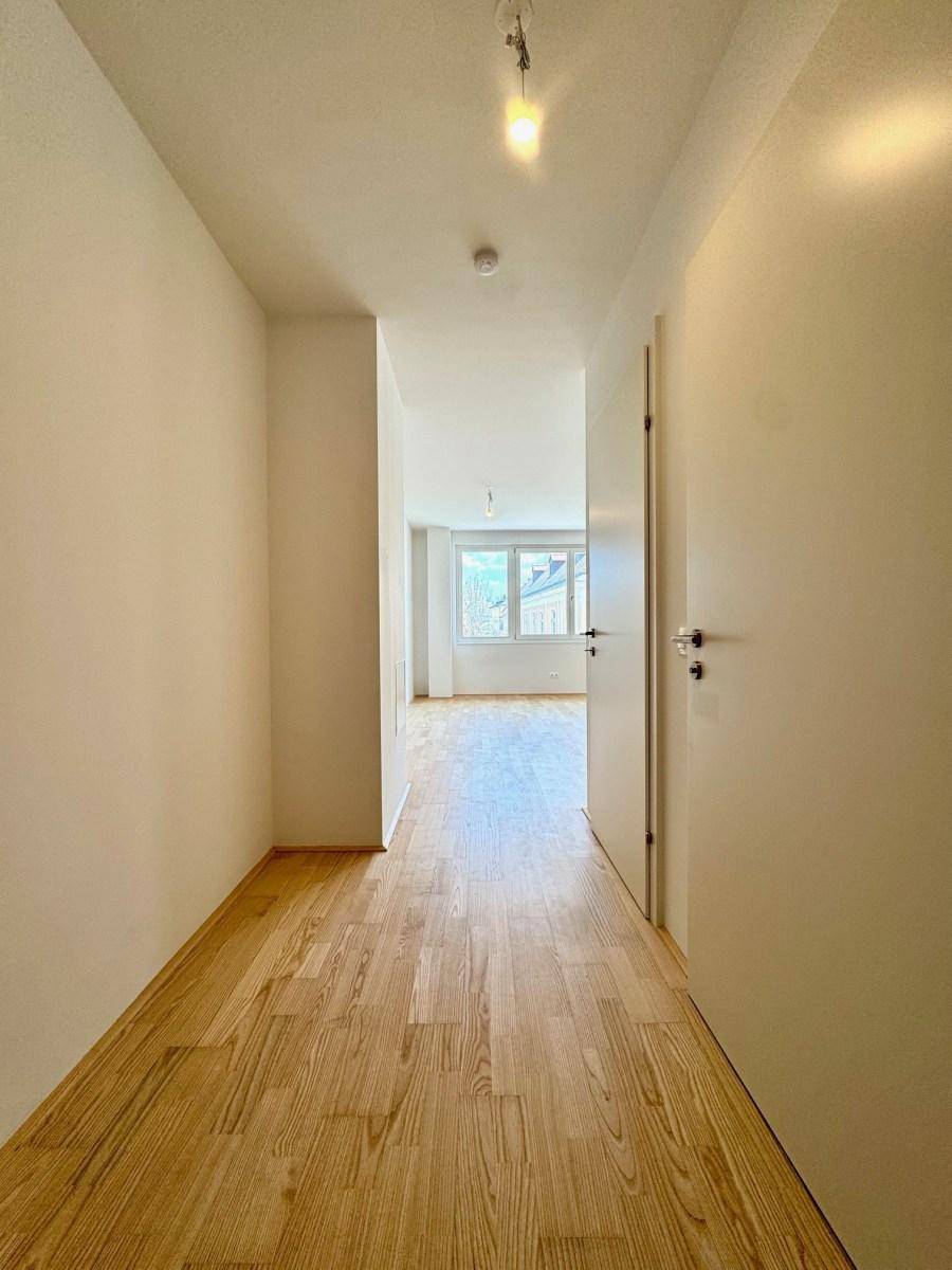 Langer, heller Flur mit Holzparkett, der zu den Wohnbereichen der Wohnung führt.