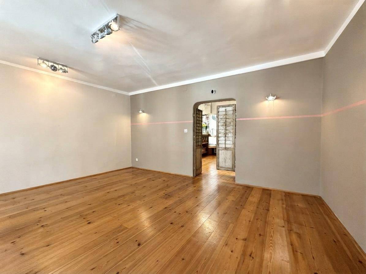 Heller Geschäftsraum mit Holzdielenboden und einem offenen Durchgang zu weiteren Räumen im hinteren Bereich des Gebäudes.