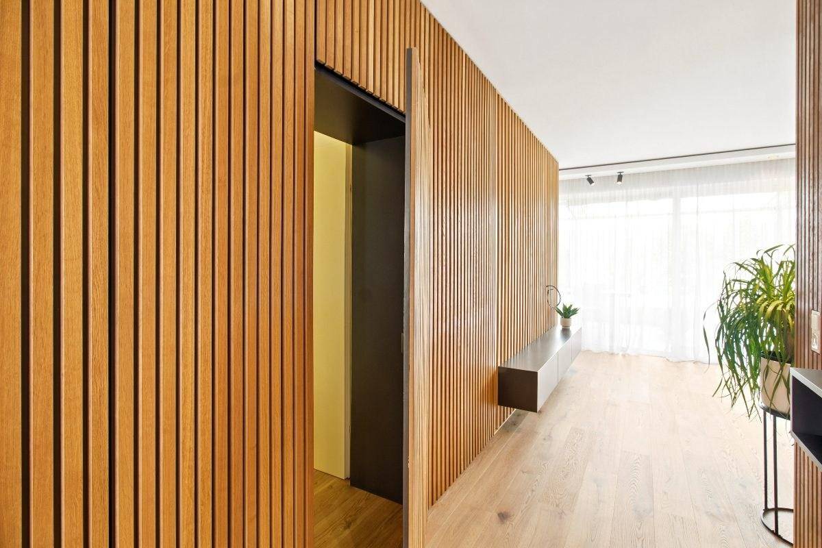 Moderner Flur mit Holzlamellenwand und integrierter Tür zu einem weiteren Raum.
