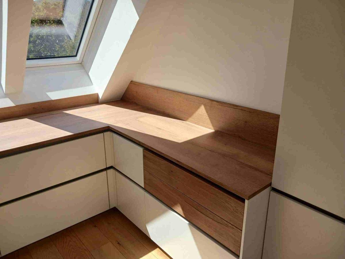 Elegante Einbauschränke mit Holzoberflächen, perfekt in die Dachschräge integriert, bieten praktischen Stauraum.